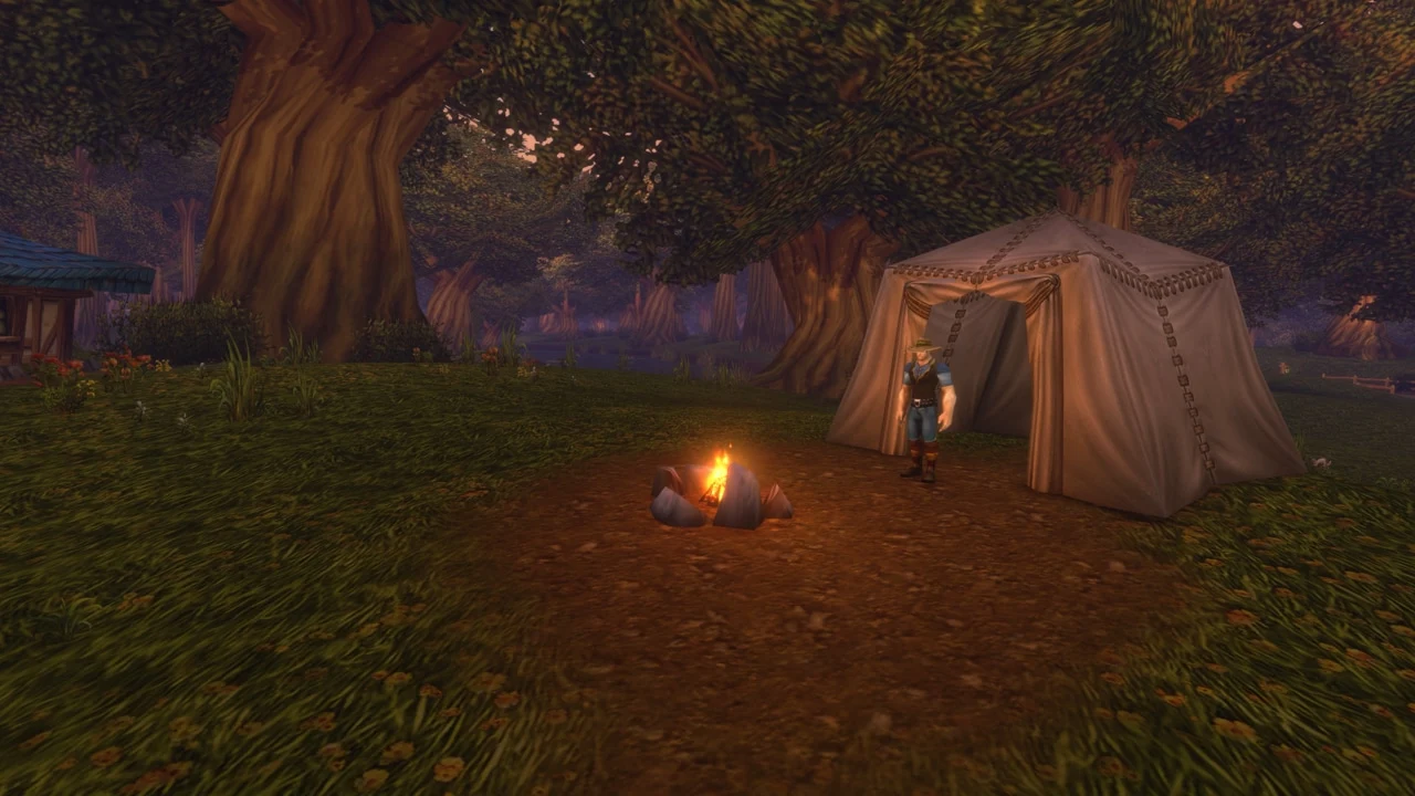 A campfire glowing beside a tent beneath the trees